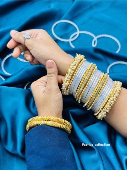 Elegant white and gold festive bangles set worn on wrists over a blue satin background